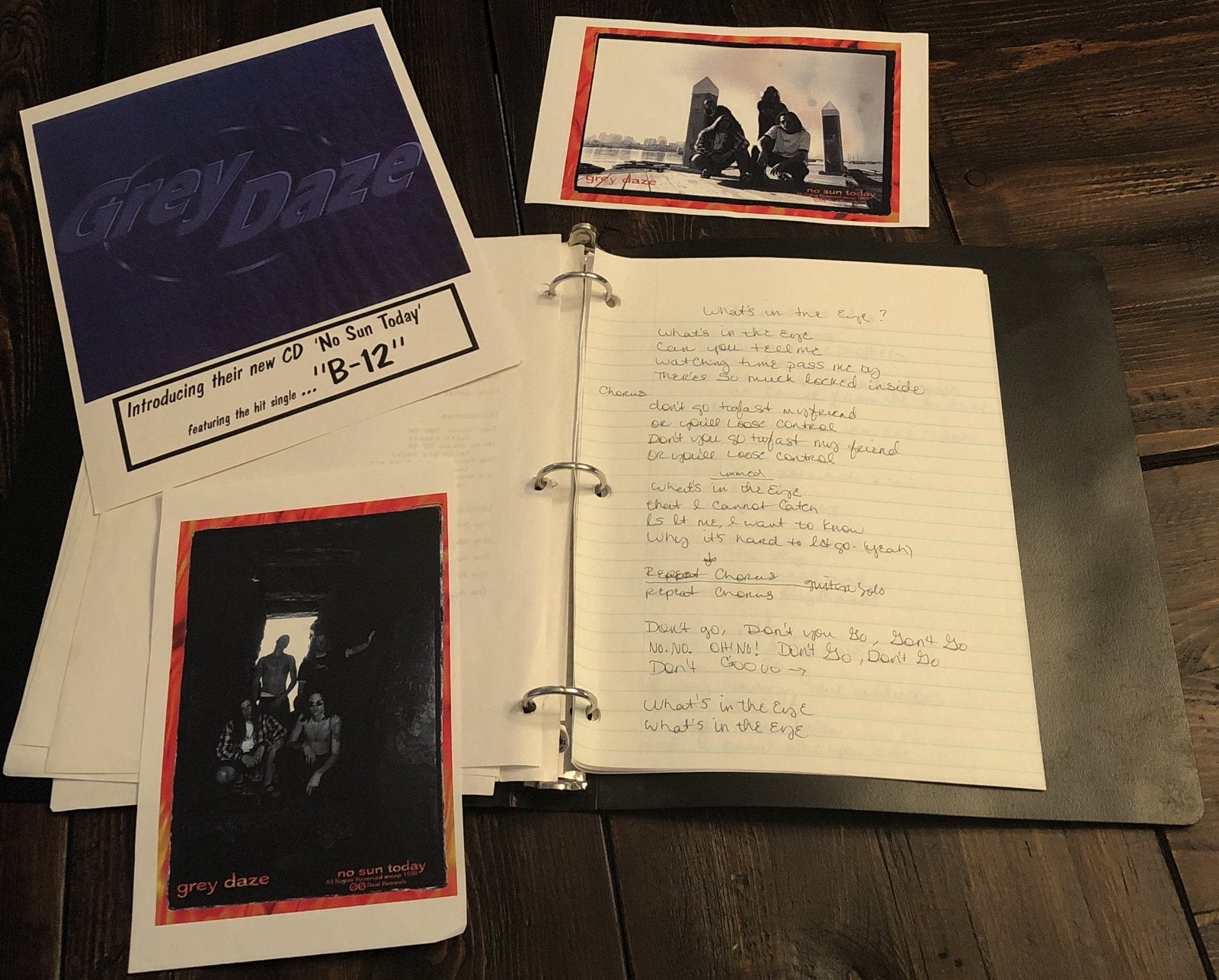 The original lyric binder, the No Sun Today promo cards and the B-12 single sheet on a wooden table